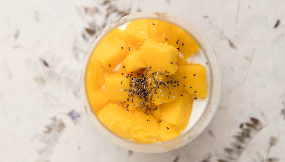 Yogurt dessert topped with mango chops and chia seeds.