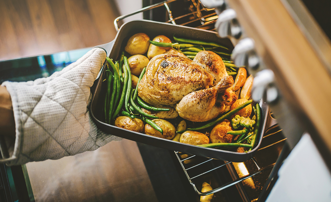 Cook taking ready chicken from the oven