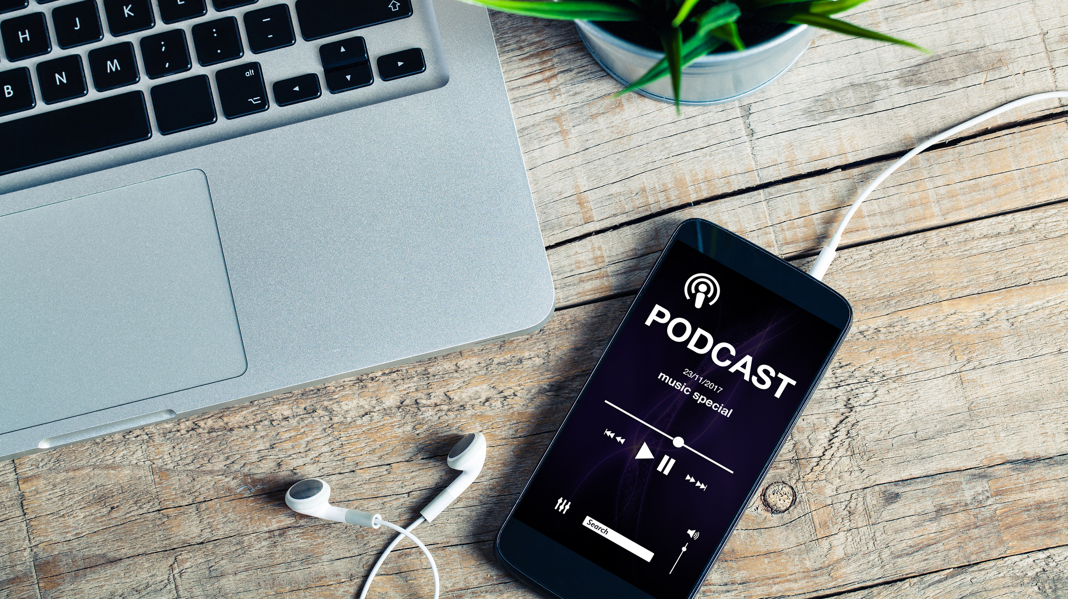 Mobile phone placed on a wooden desk with podcast app in the screen.