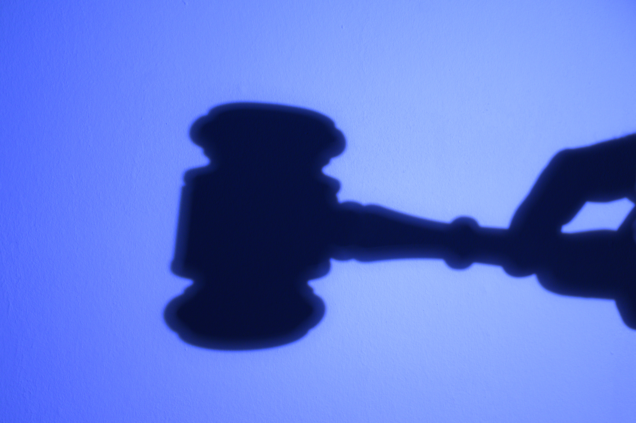 Silhouette of hand with a judge’s gavel. Suspense of payments.