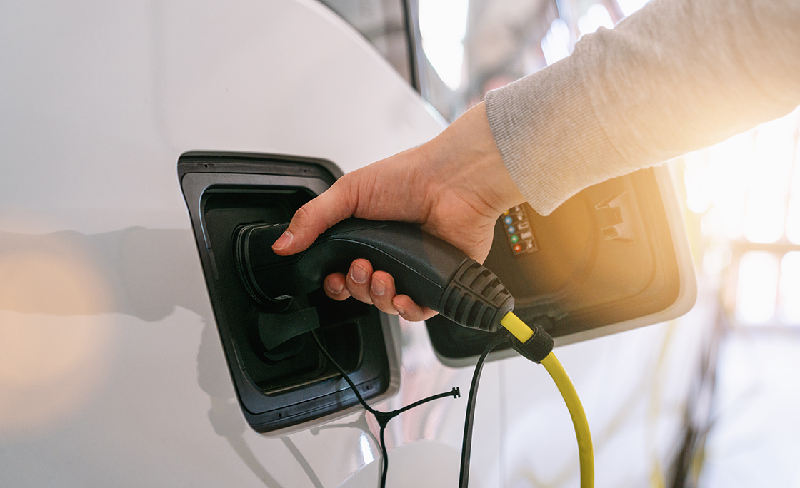 Cropped Hand Of Person Holding Cable In Electric Car For Charging