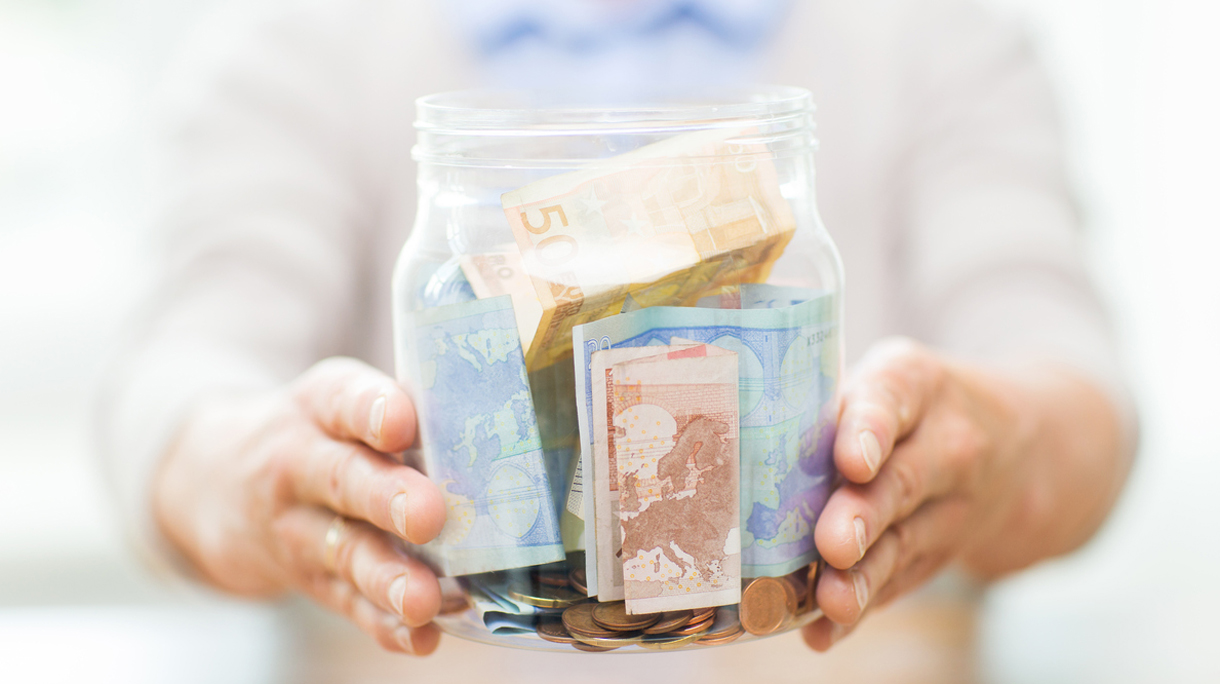 close up of senior woman with money in glass jar