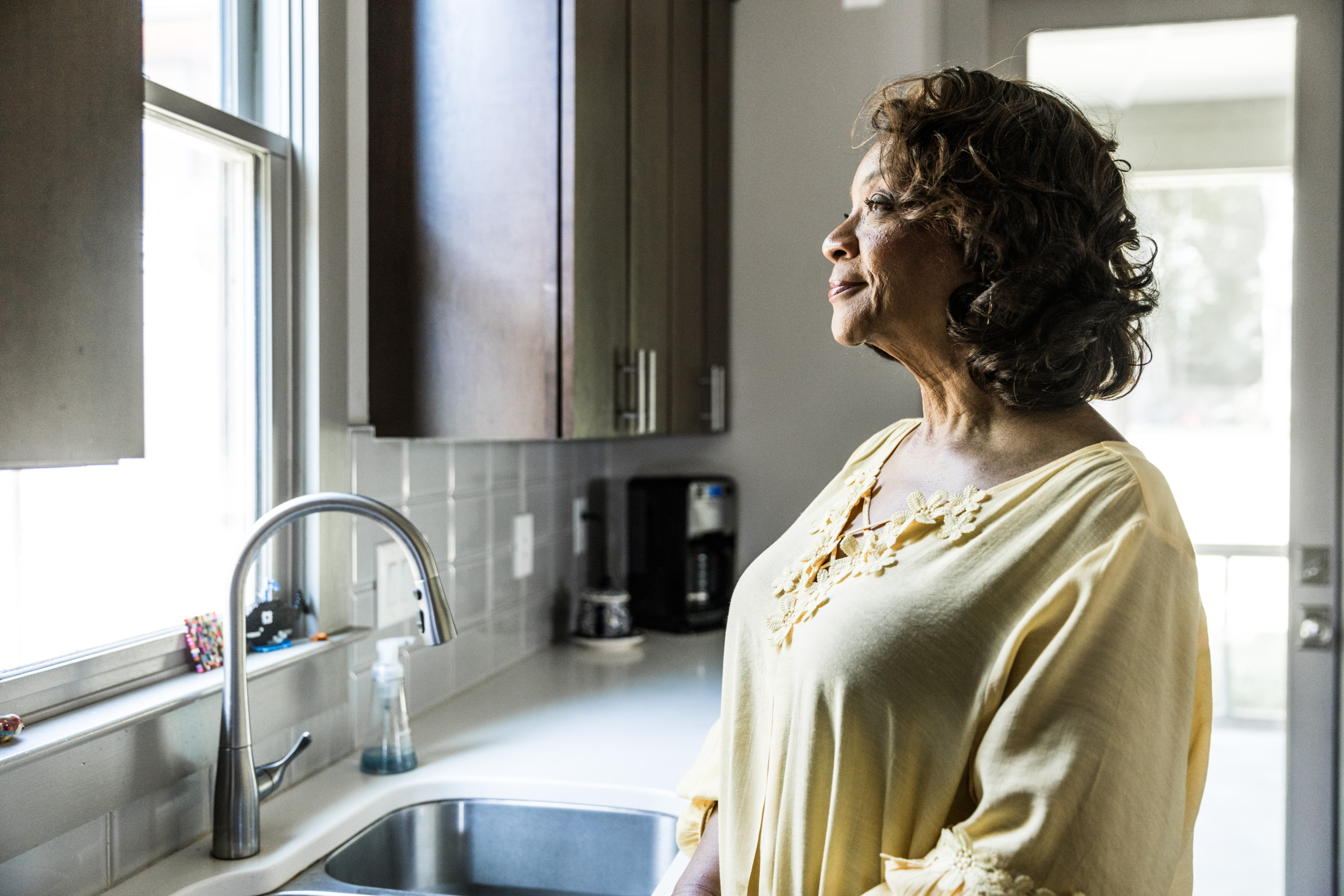 Senior woman looking out kitchen window