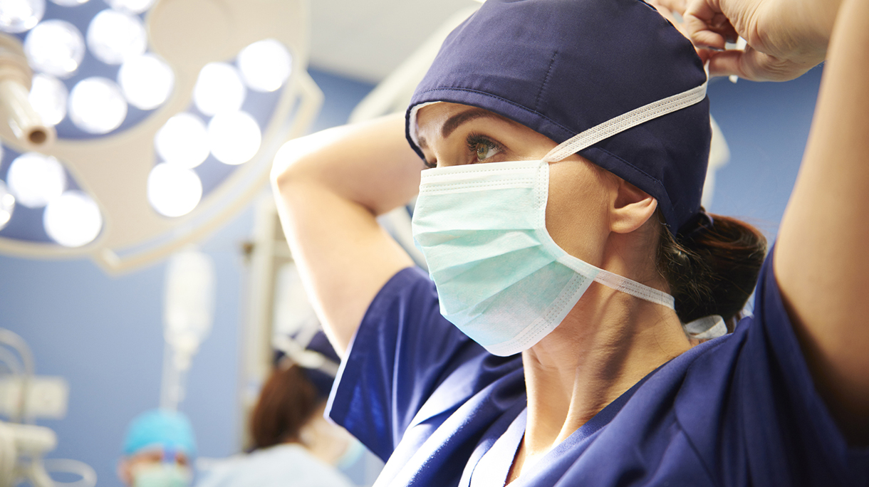 Low Angle View Of Doctor Tying Surgical Mask In Hospital