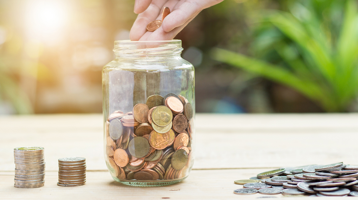 Cropped Hand Of Person Pouring Coins In Jar