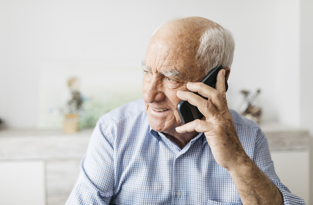 Happy senior man using smartphone at home