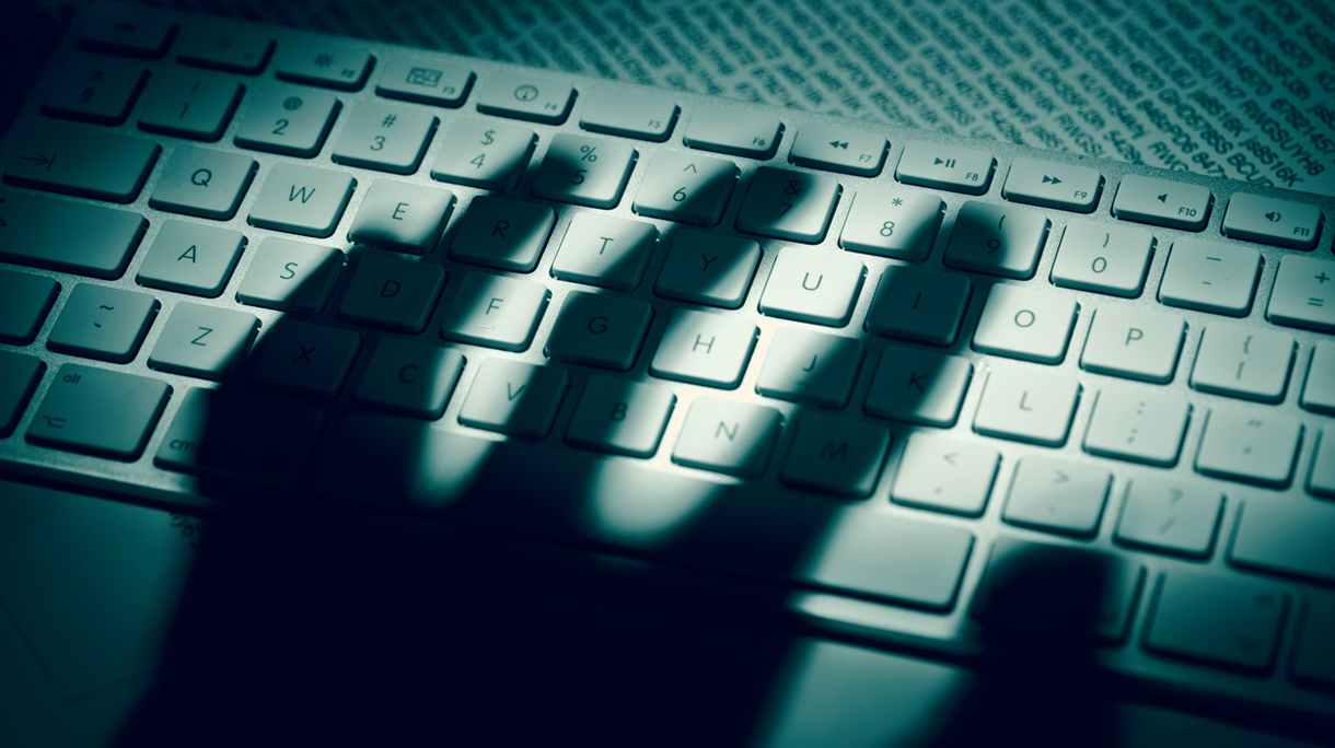 Data thief’s hand shadow on computer keyboard