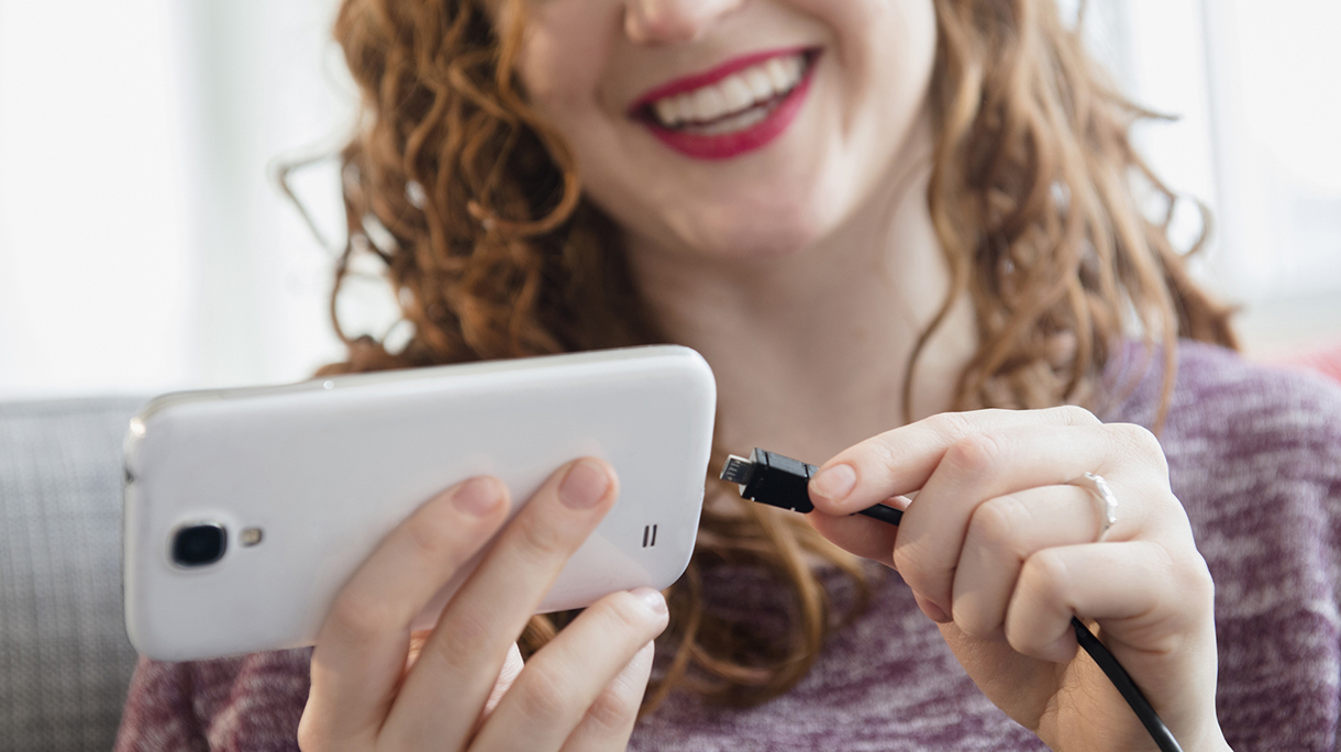 Caucasian woman connecting cord to cell phone