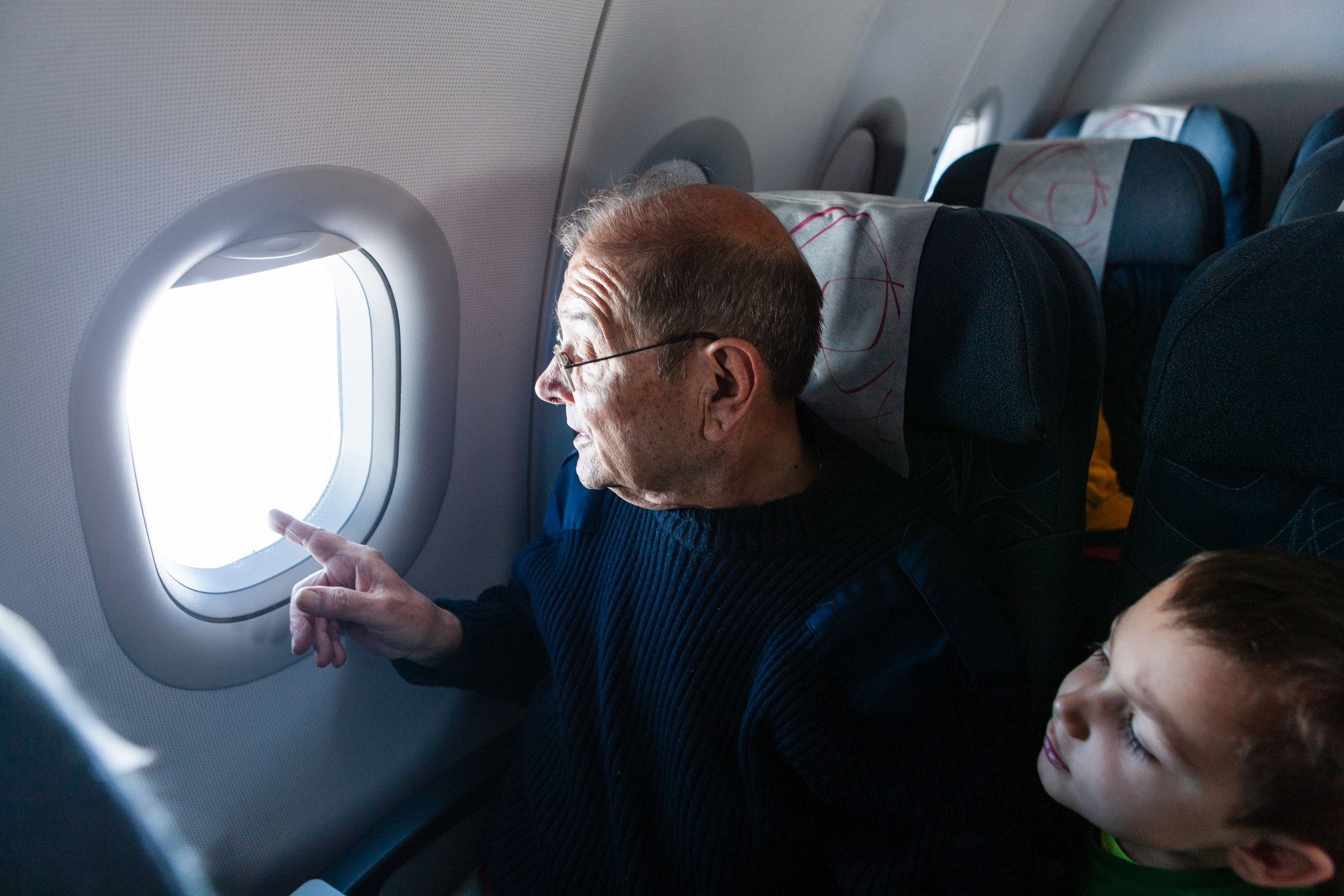 Grandfather and grandson looking through airplane window