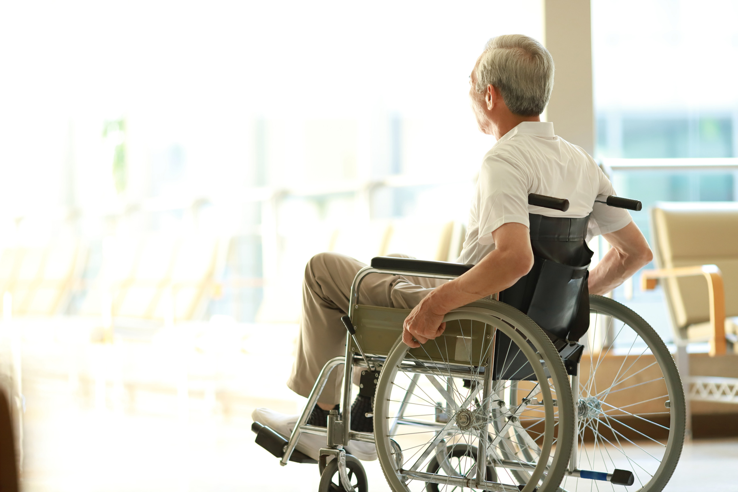 Senior man in wheelchair looking out window