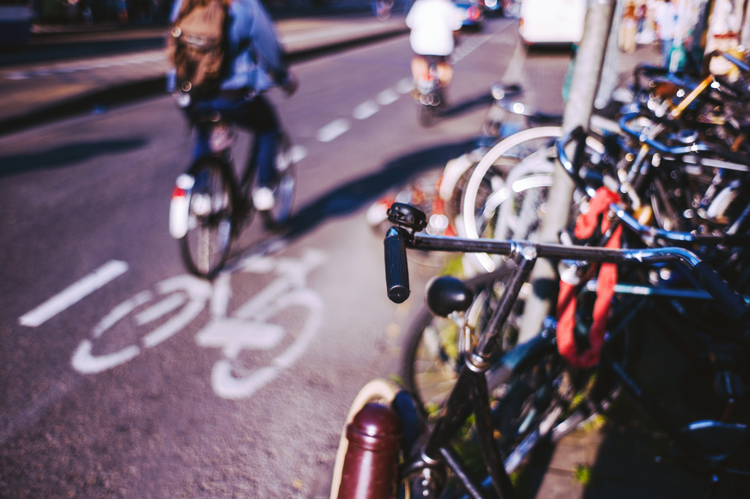 Parked bicycles on the street, cyclists passing by on the cycle lane