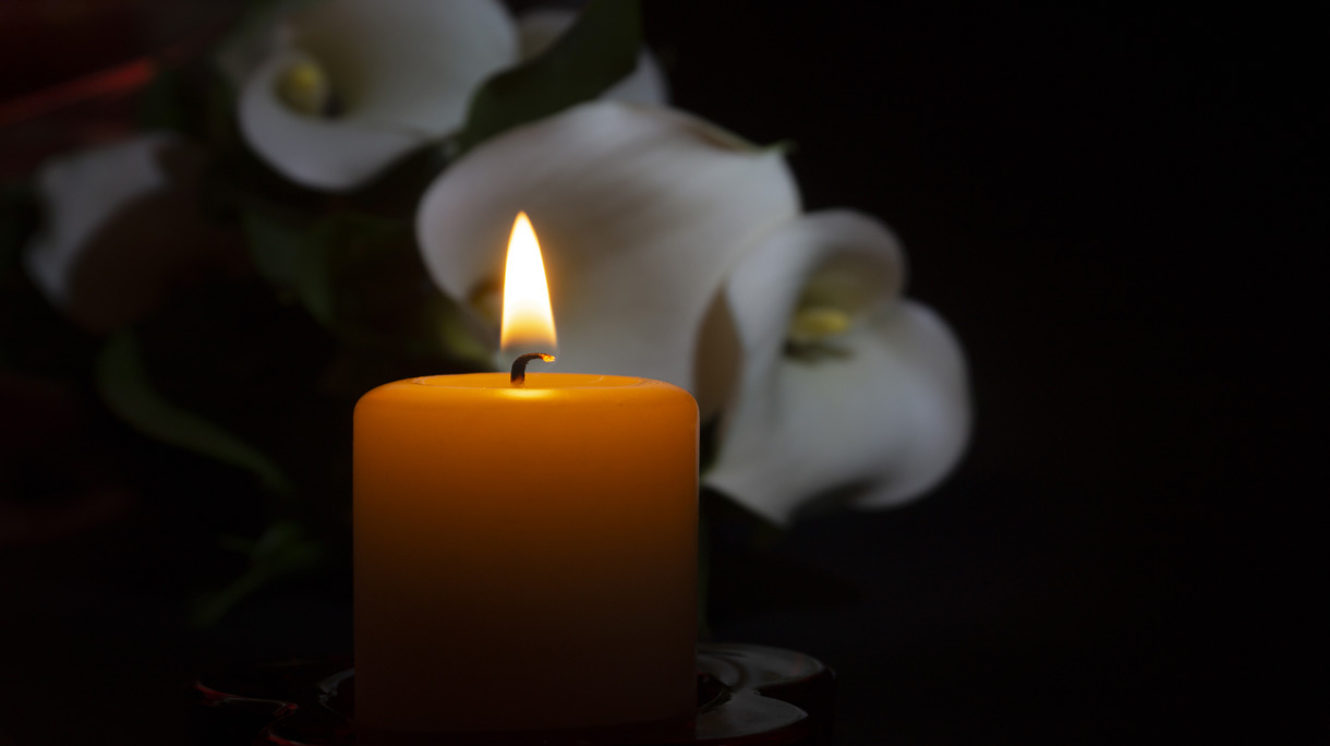 Close up of orange candle flame and lily flowers