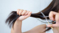 Midsection Of Woman Cutting Hair Against White Background