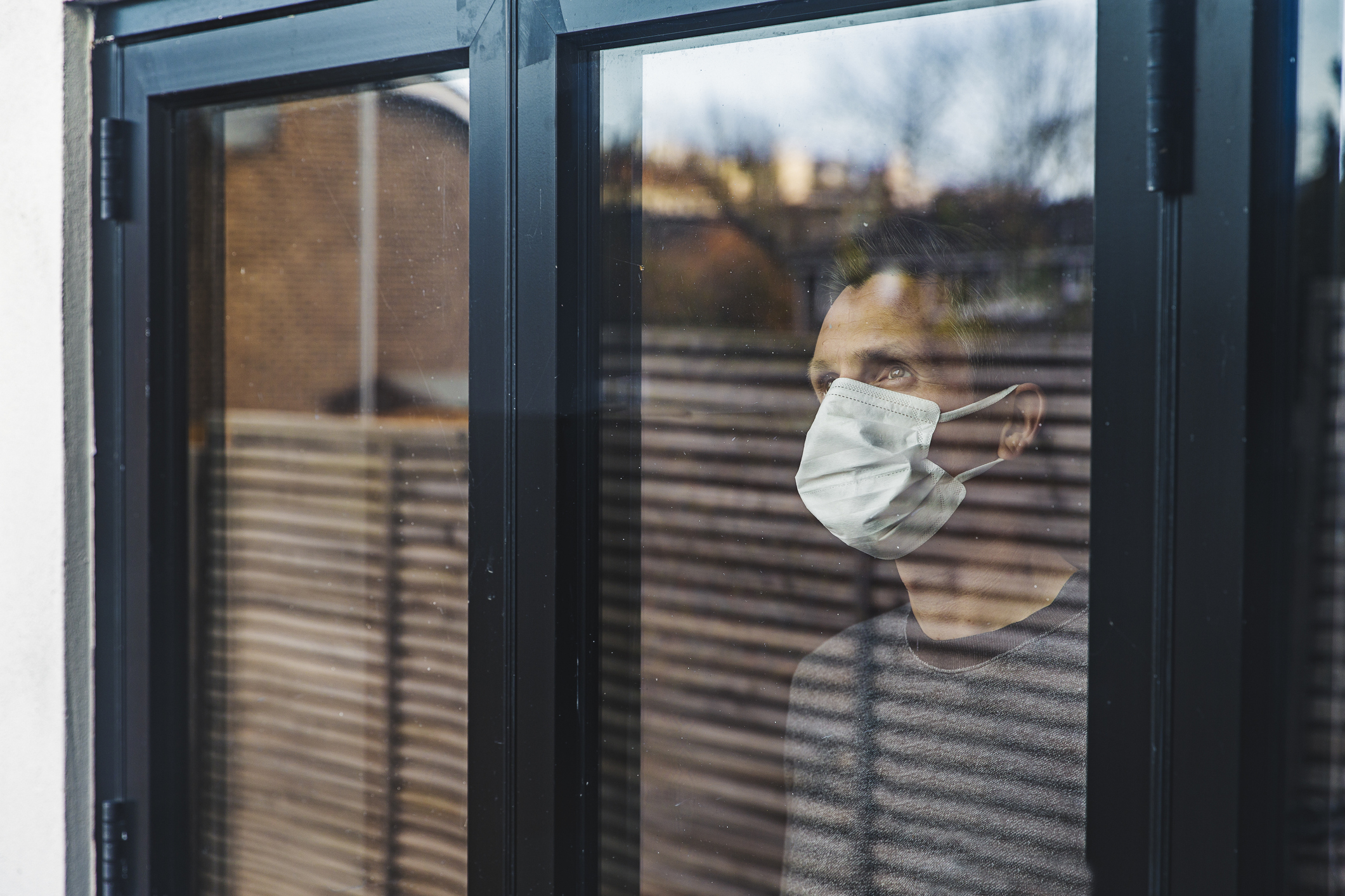 Man with mask looking out of window