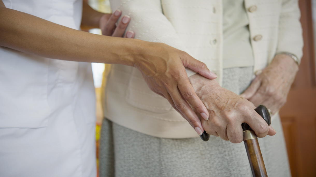 Close up of caretaker helping older woman walk