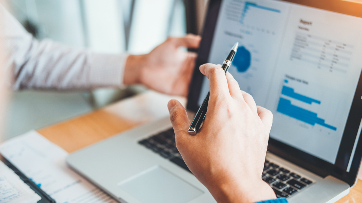 Cropped Hands Of Colleagues Discussing Graphs Over Laptop On Desk In Office