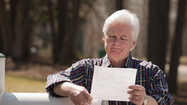 USA, Virginia, Richmond, senior man reading letter by mailbox