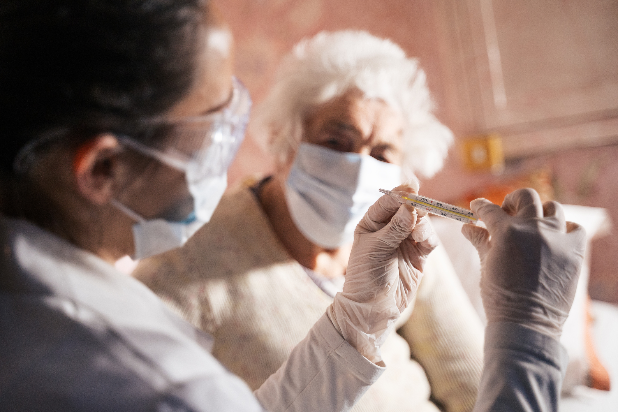 Coronavirus protection during the quarantine. Female doctor doing medical exam to a senior woman at her home.