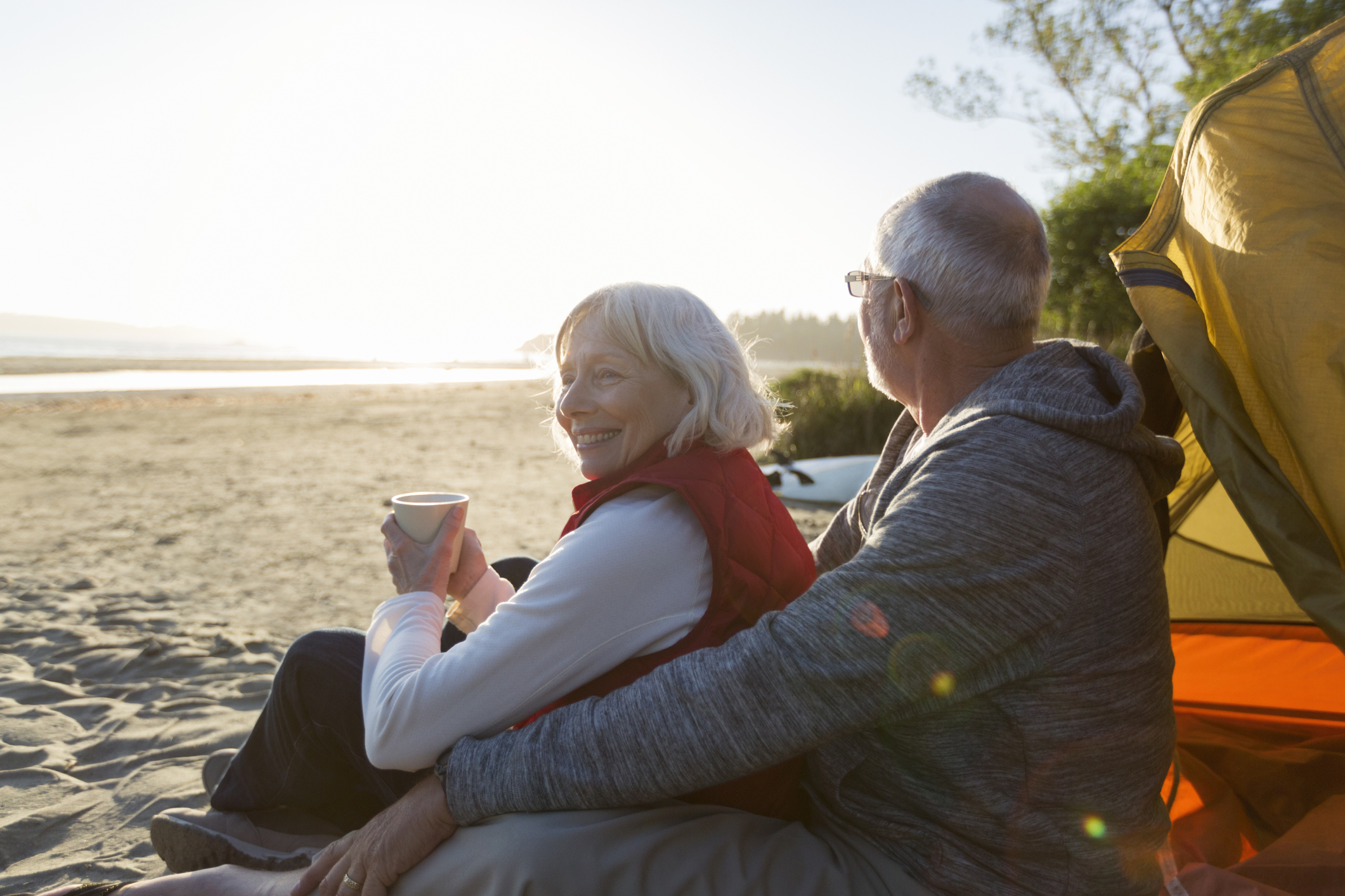 Senior couple camping on beach looking at ocean view