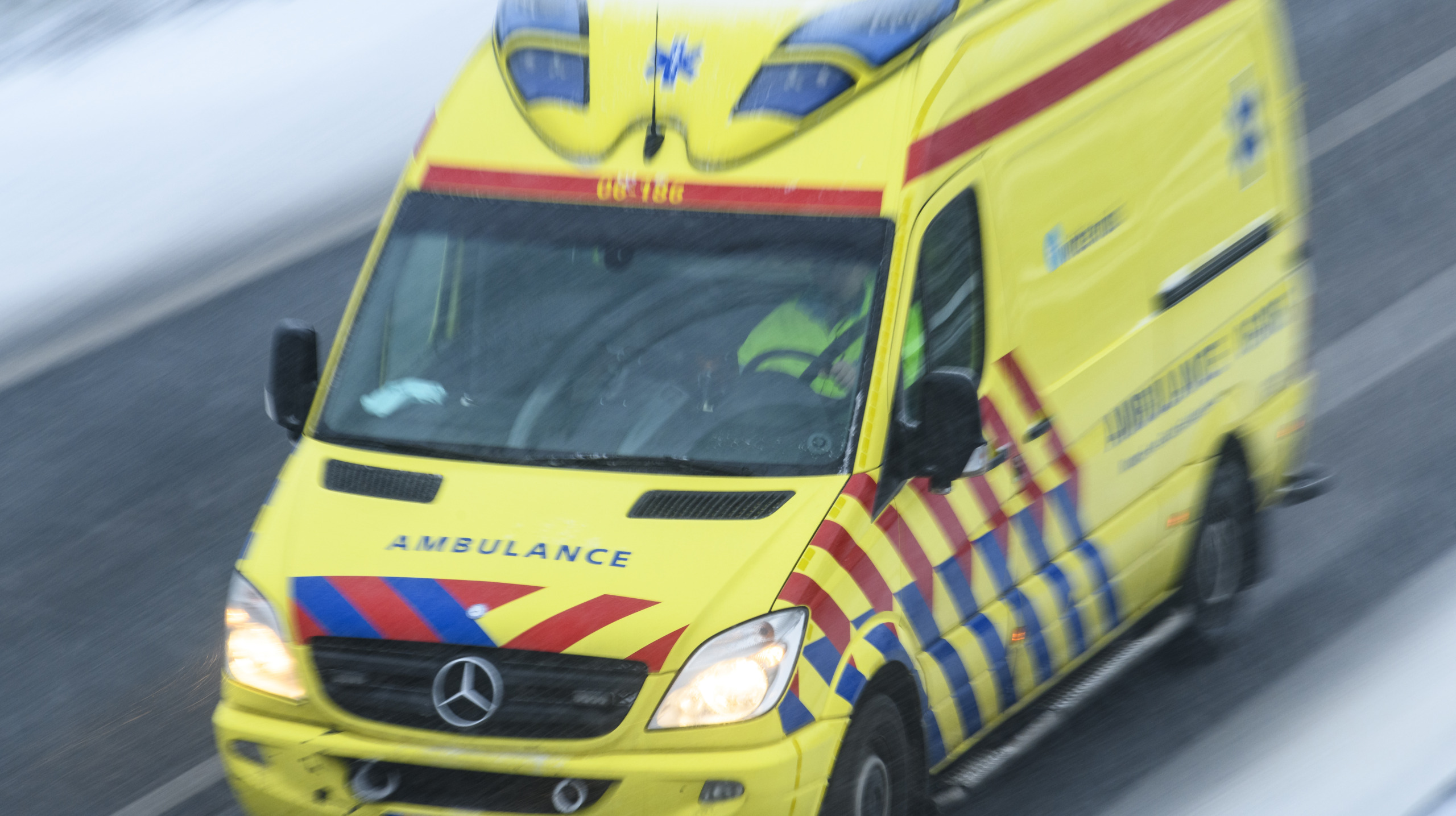 Ambulance rushing to an accident at high speed on a highway during a snow blizzard