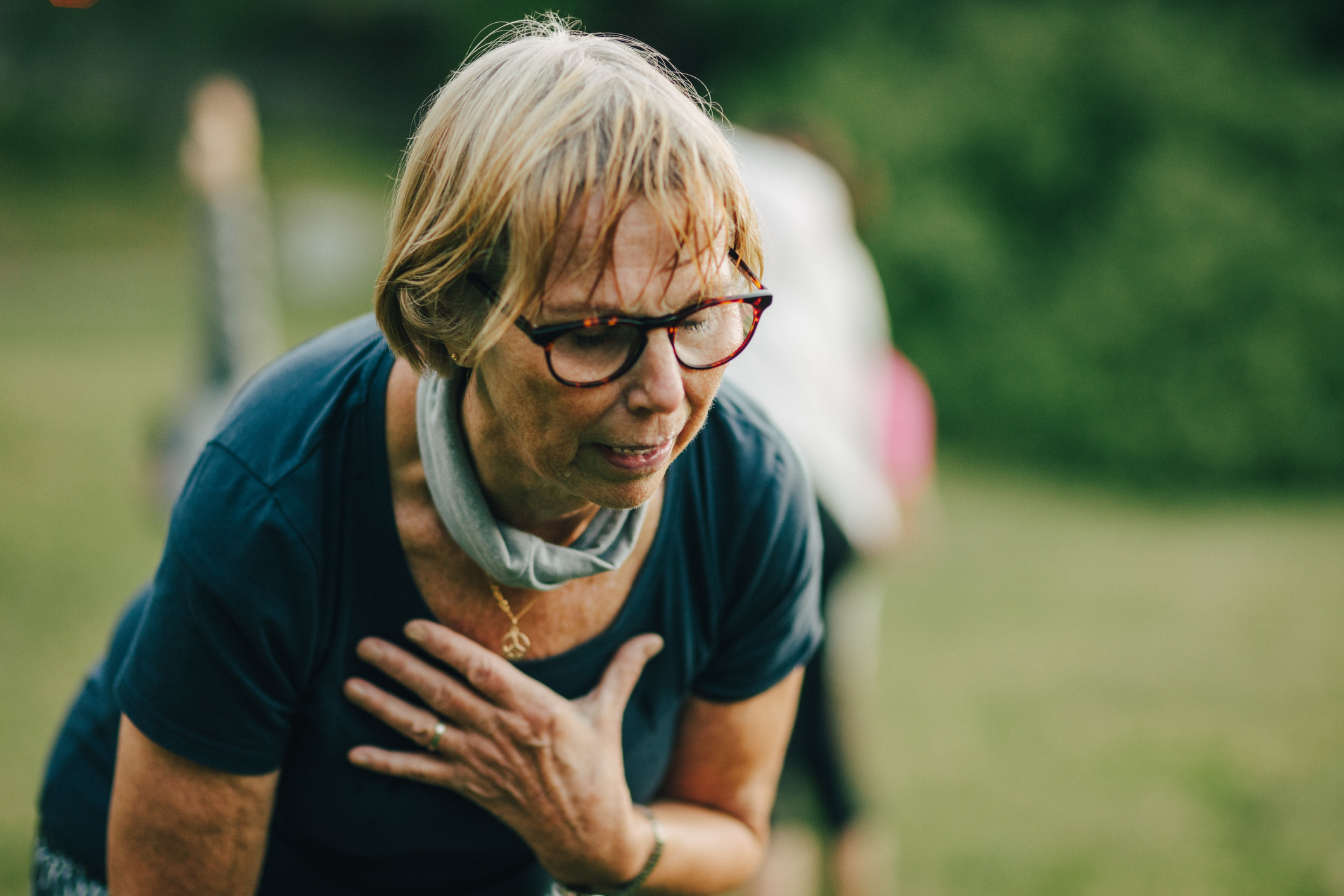 Tired senior woman with eyeglasses sweating after exercise at park