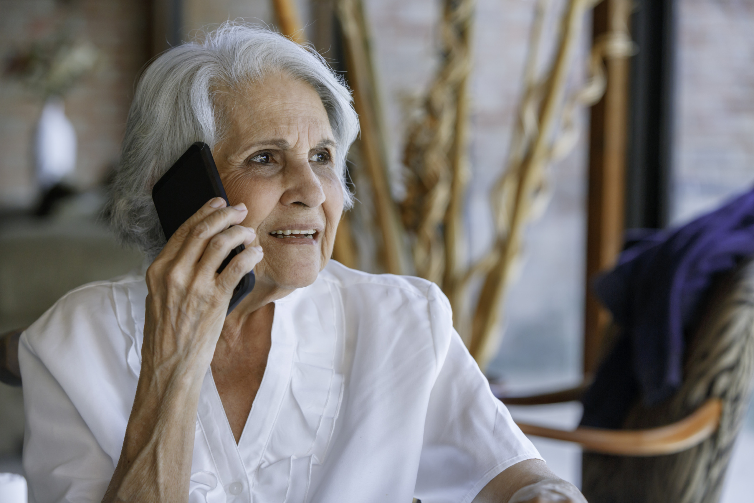 Relaxing senior woman using mobile phone while sitting in living room