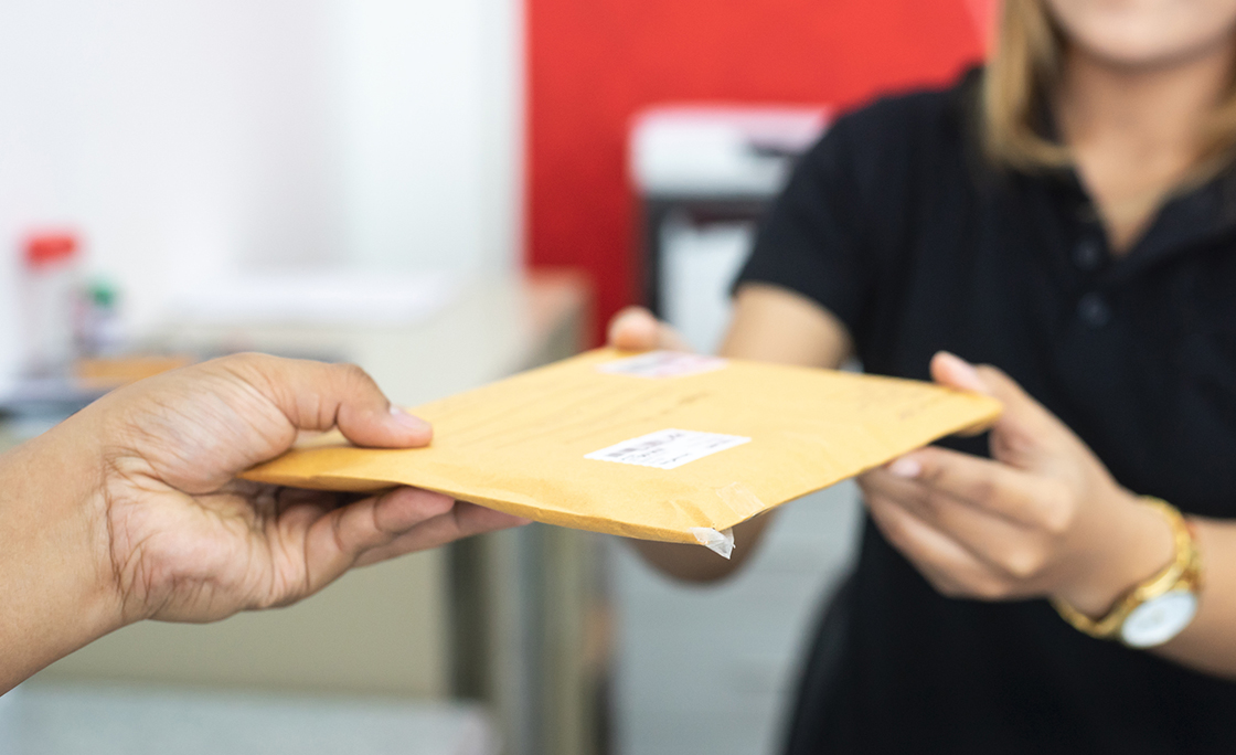 male hand send mail envelope to the female of post office before sending