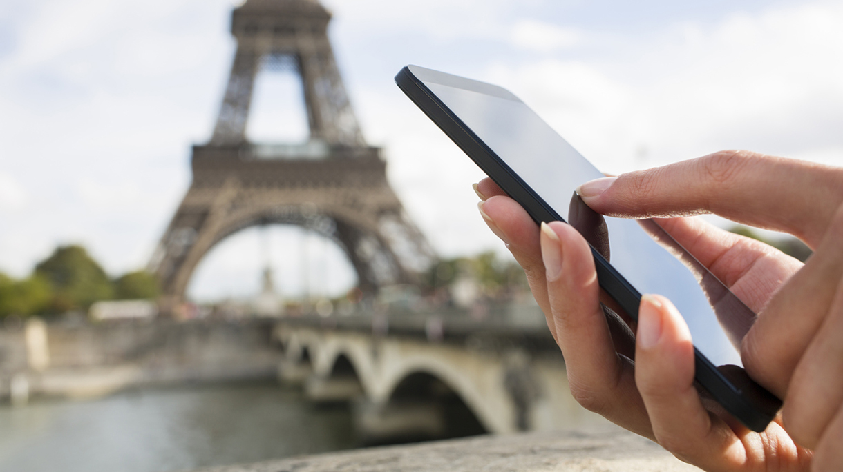 Woman using her Mobile Phone in front of Eiffel Tower