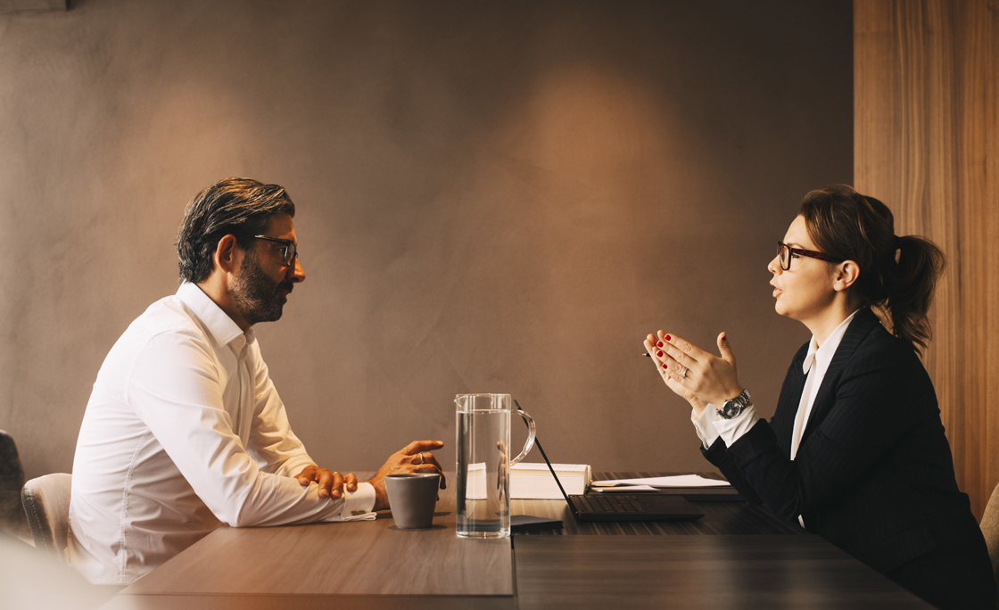Side view of female lawyer explaining mature client in meeting at office
