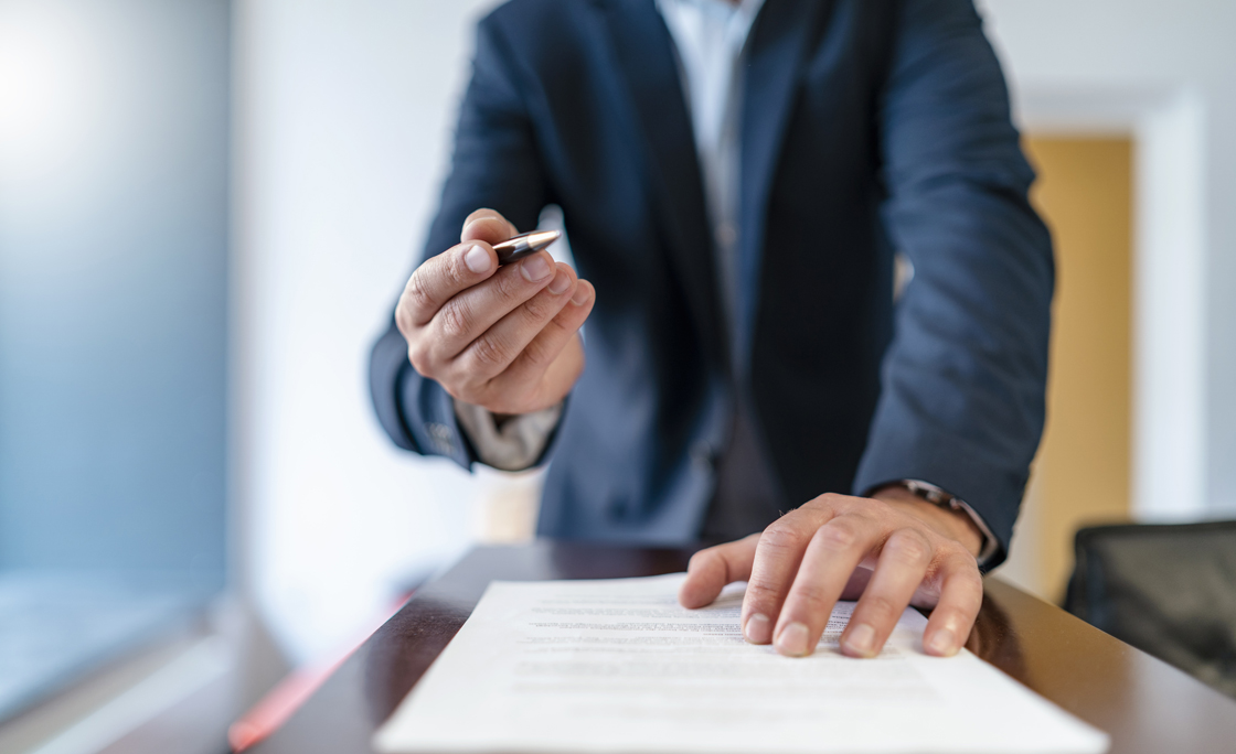 Close-up of businessman in office presenting ballpen and contract