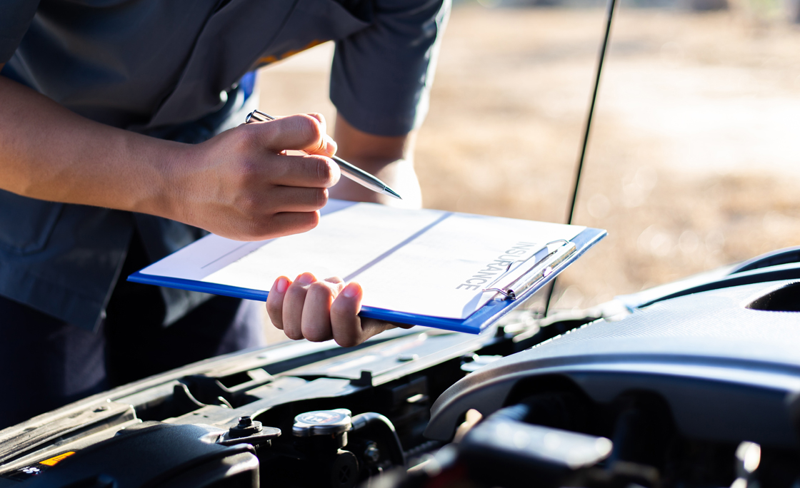 Cropped Hand Of Man Holding Insurance Document While Standing By Car
