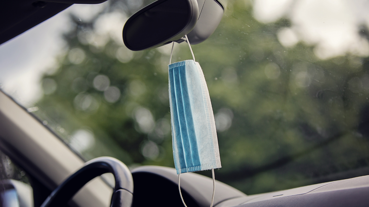 Face protective mask hanging at rear view mirror in car