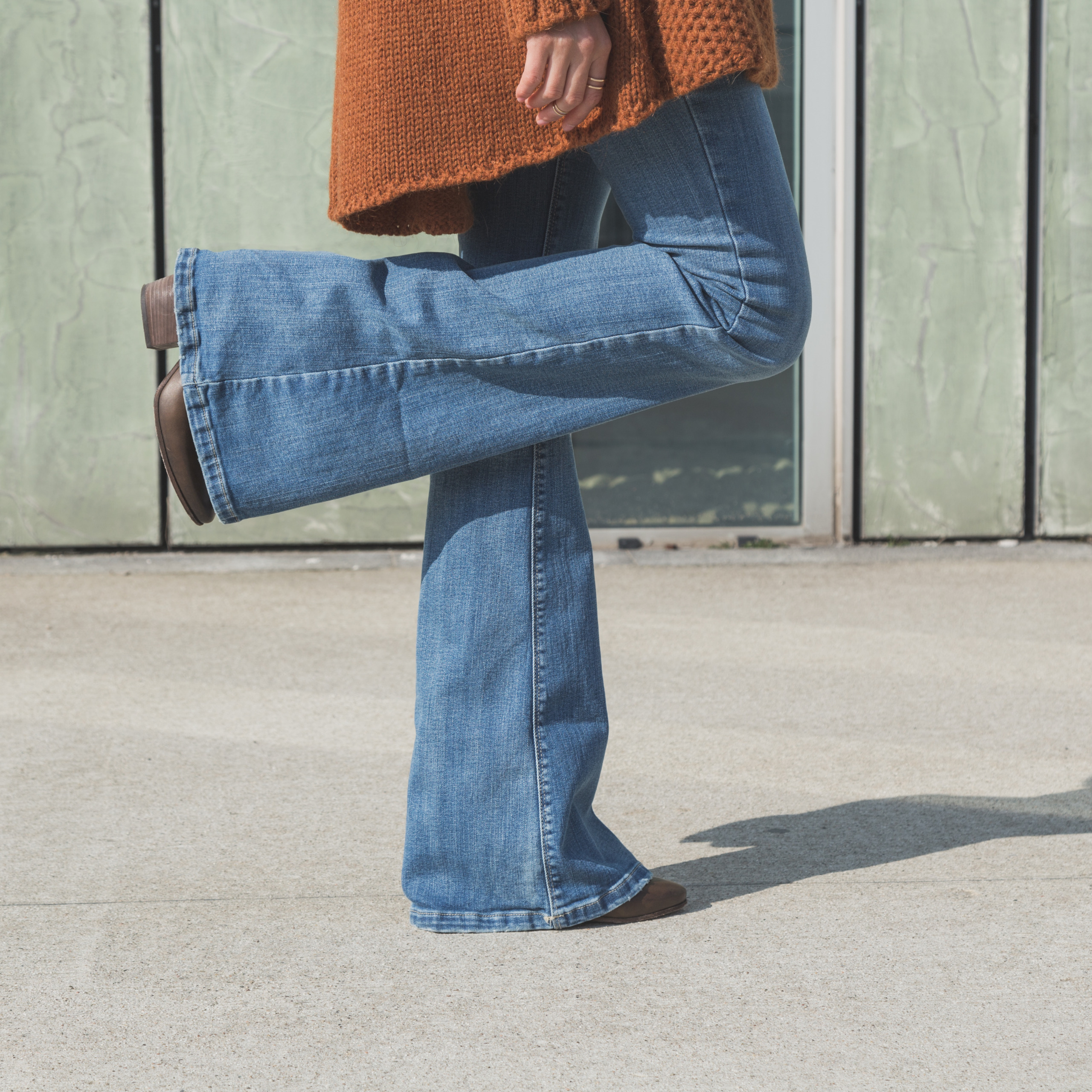 Woman in blue jeans standing on one foot on cement floor