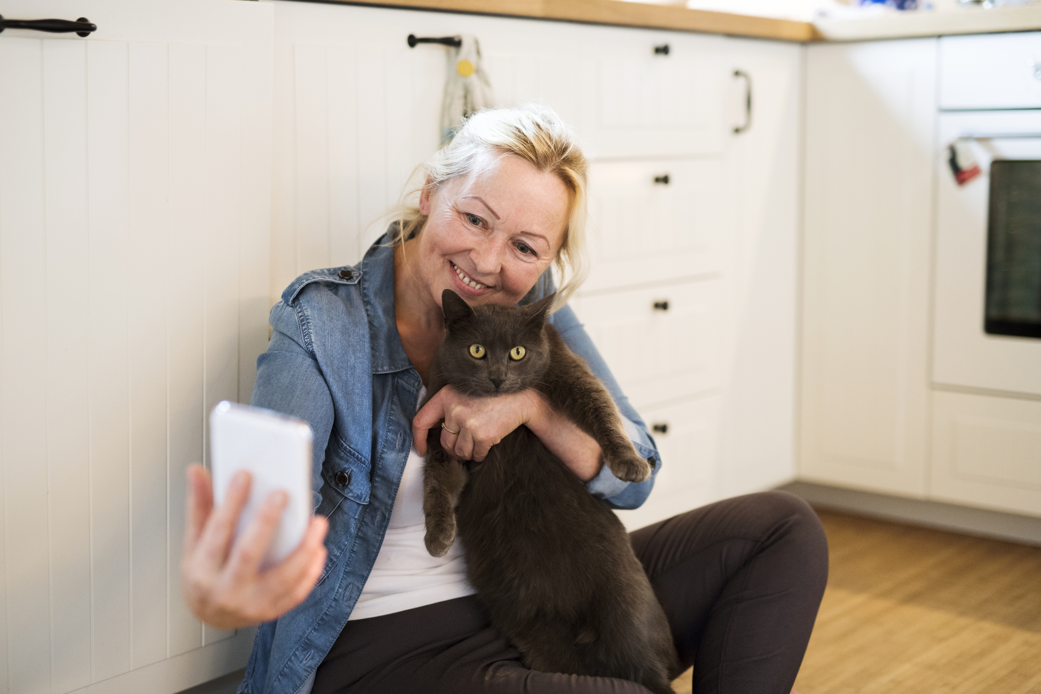 Senior woman with her cat at home taking selfie.