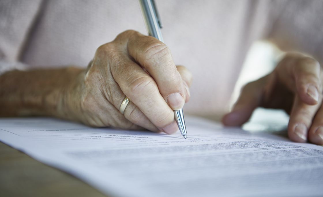 Senior woman’s hand signing a document, close-up
