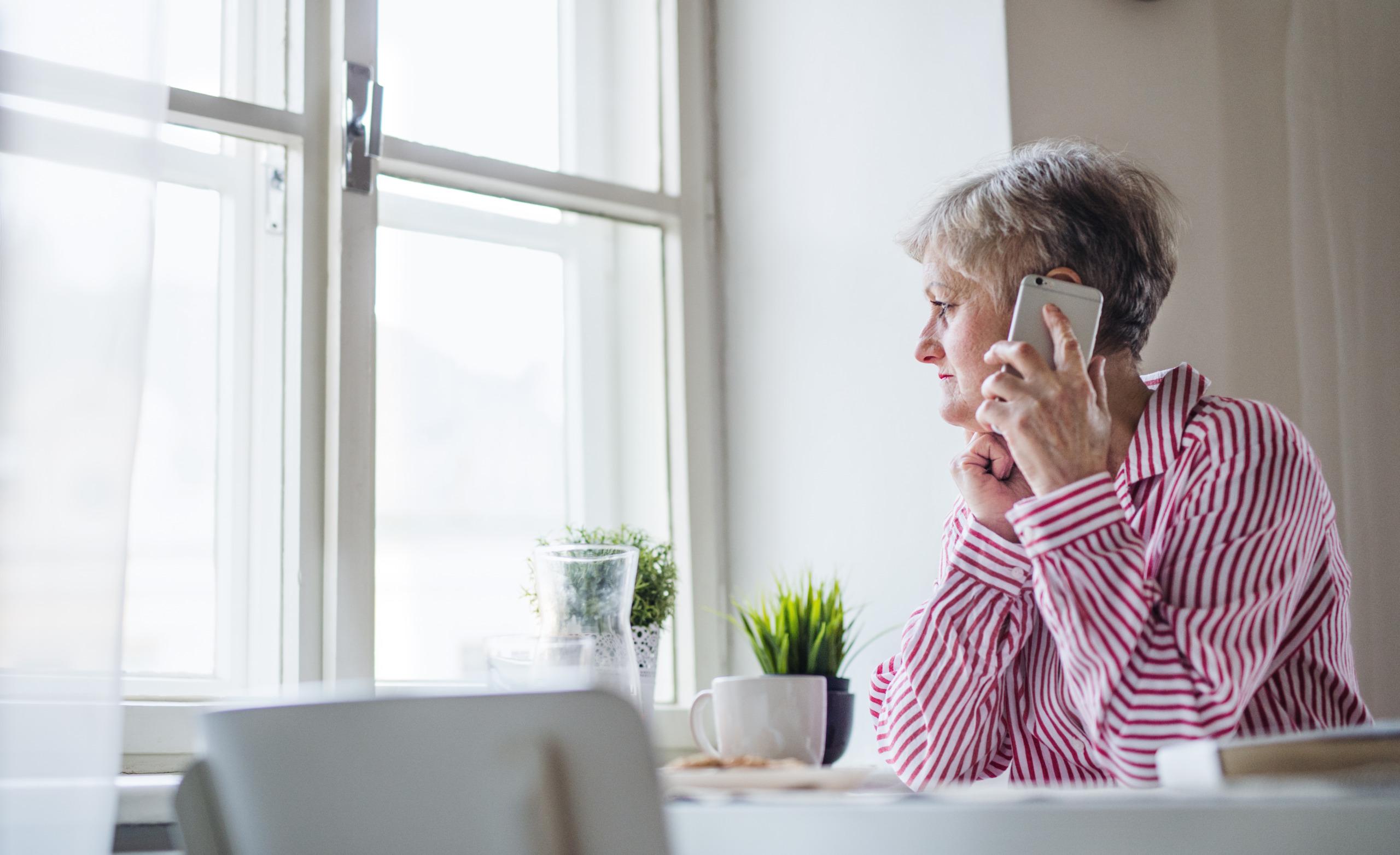 An active senior woman working in home office, lusing smartphone.