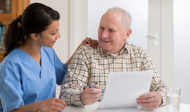 Home caregiver and elderly man reading paperwork