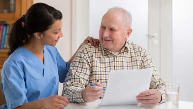 Home caregiver and elderly man reading paperwork