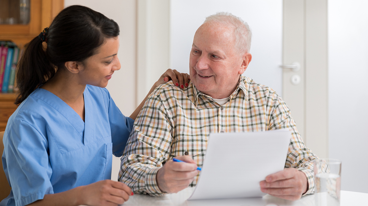 Home caregiver and elderly man reading paperwork