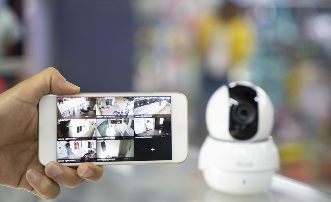 A Person’s Hand Holding Mobile Phone With CCTV Camera Footage On Screen