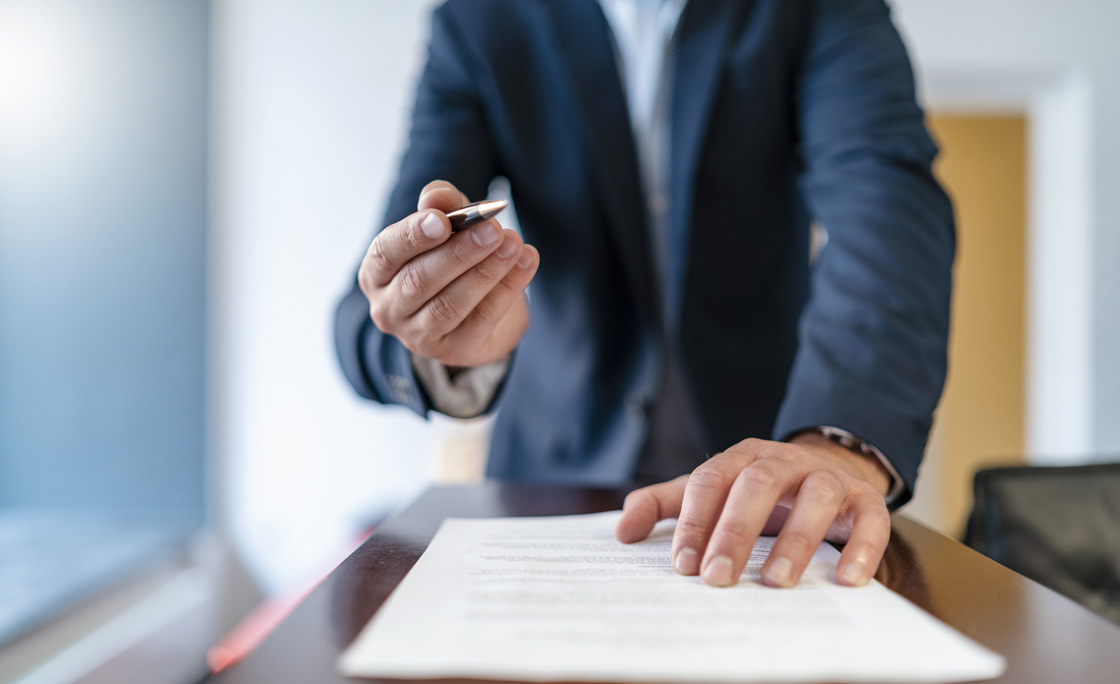 Close-up of businessman in office presenting ballpen and contract