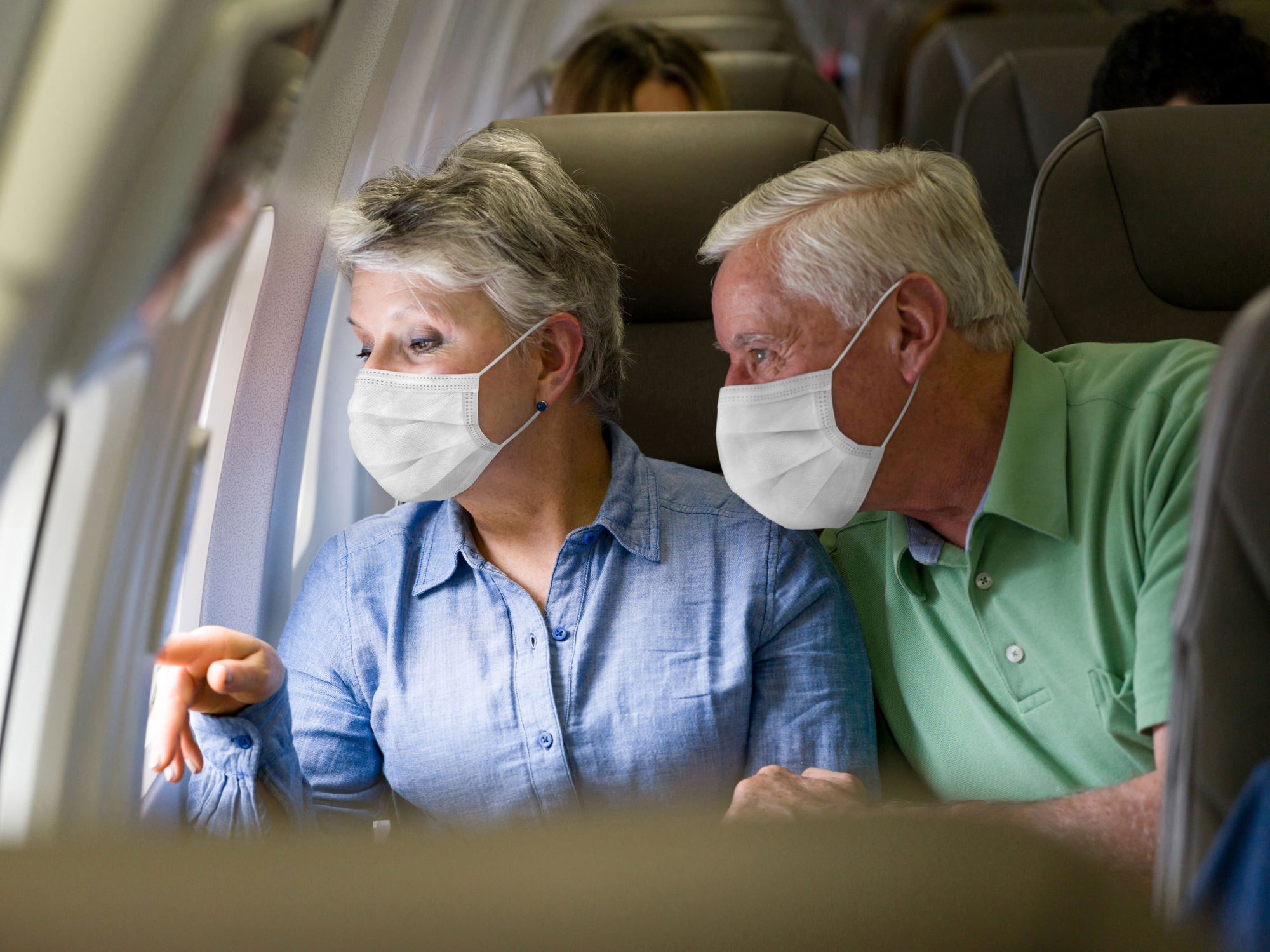 Senior couple traveling by plane wearing facemasks