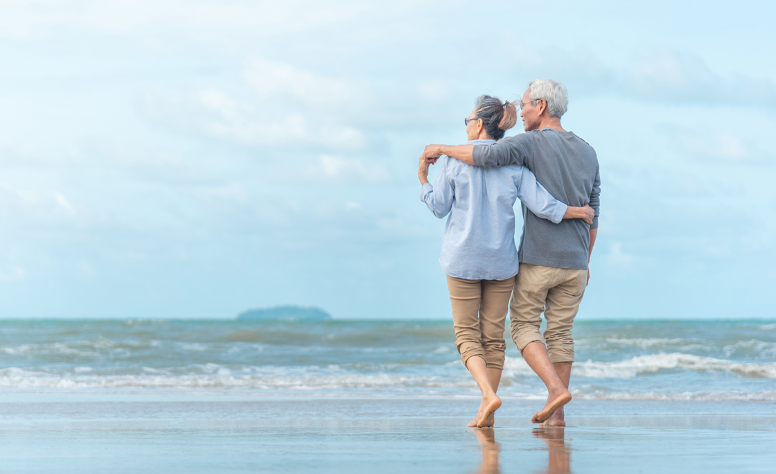 Happy senior couple on the beach. Exotic luxury resort.back view.