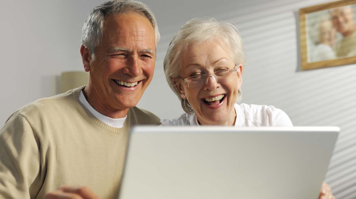 A portrait of a seniors using a laptop with a happy face