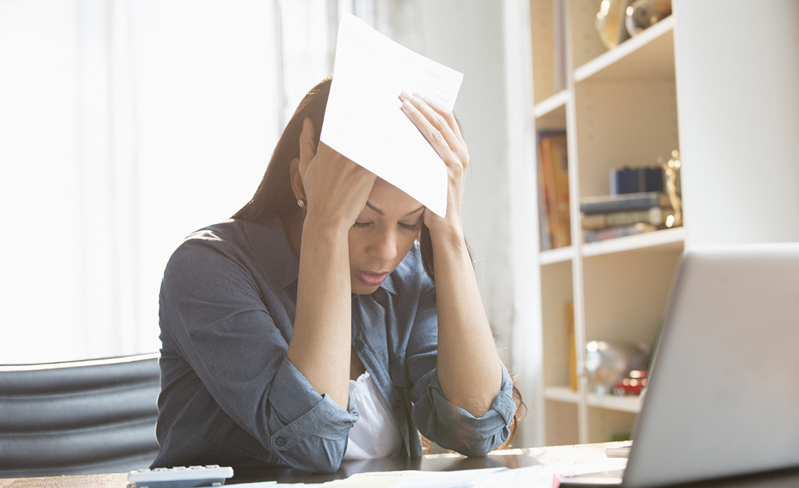 Anxious mixed race woman paying bills on laptop