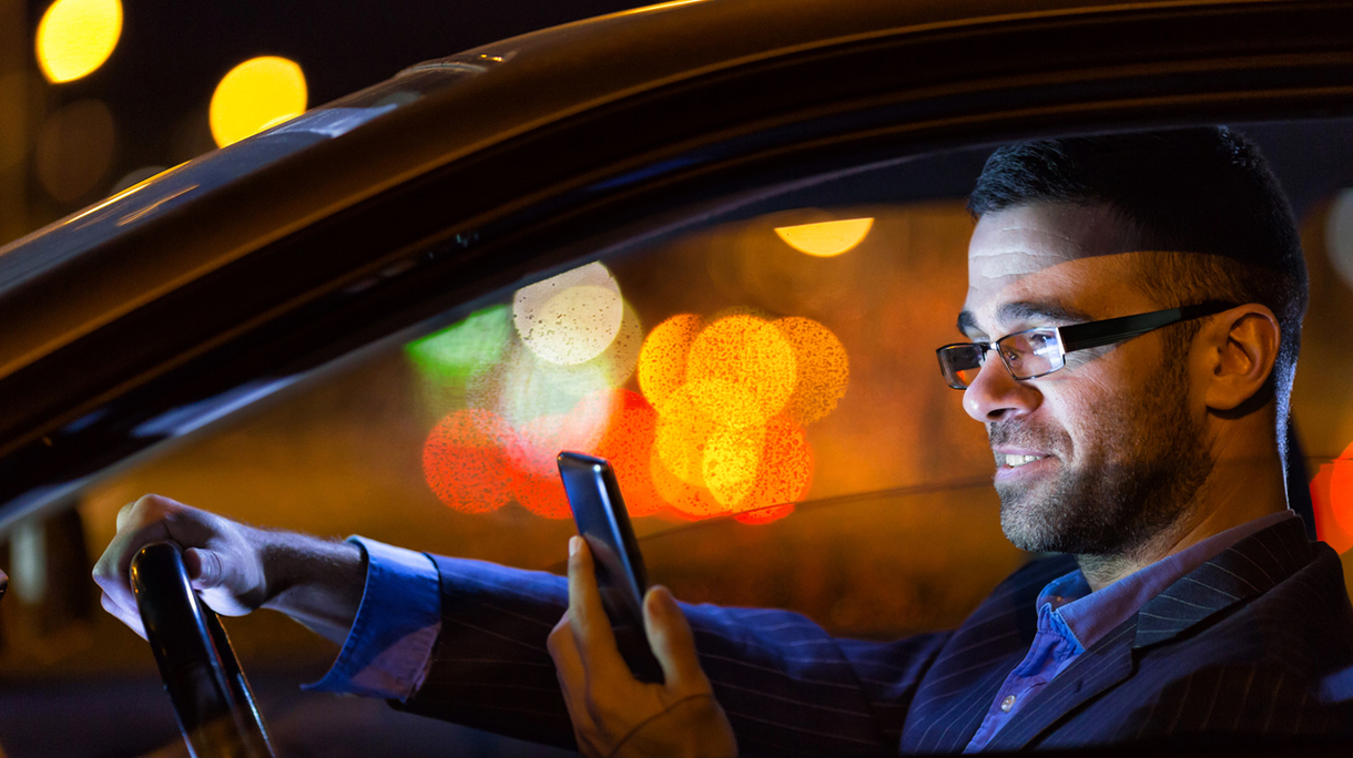 Businessman in a car at the night with smart phone