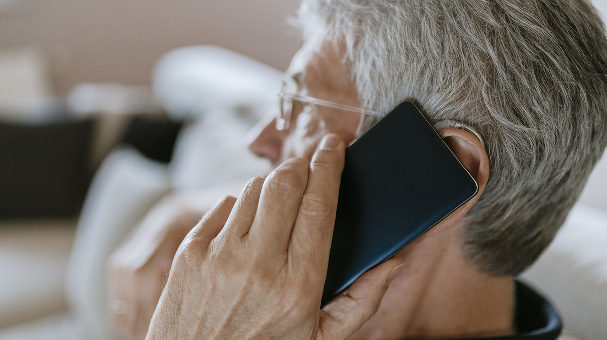 Senior man with hearing aid on cell phone