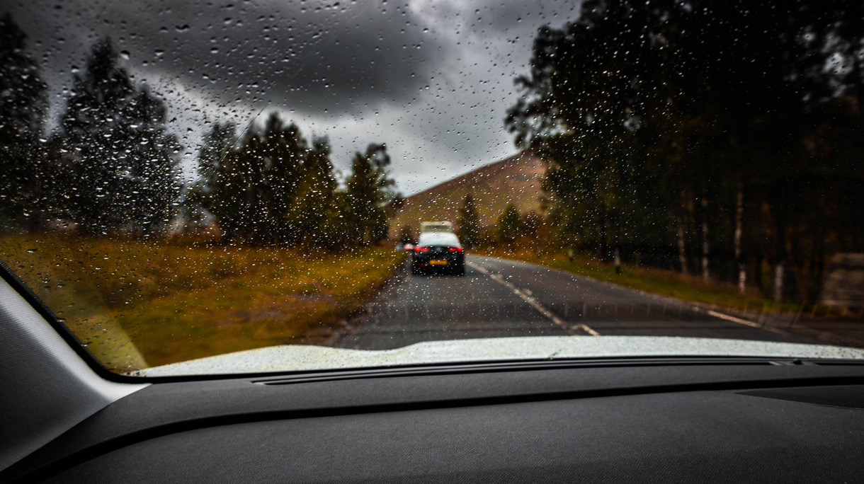 Driving car during road trip in Scotland with rainy day.