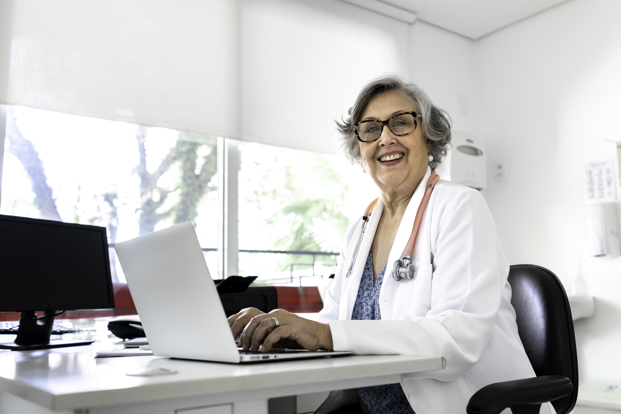 Portrait of senior female doctor using laptop at doctor’s office