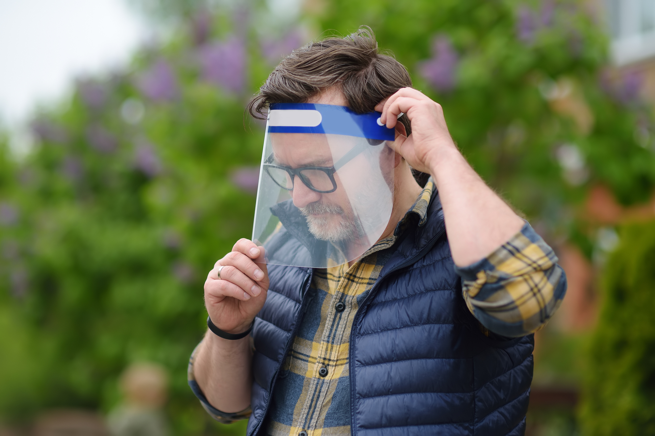 Man putting on face shield on street of city or park. Safety during COVID-19 outbreak. Lifting virus lockdown. Social distancing and face mask – security measures when exiting quarantine